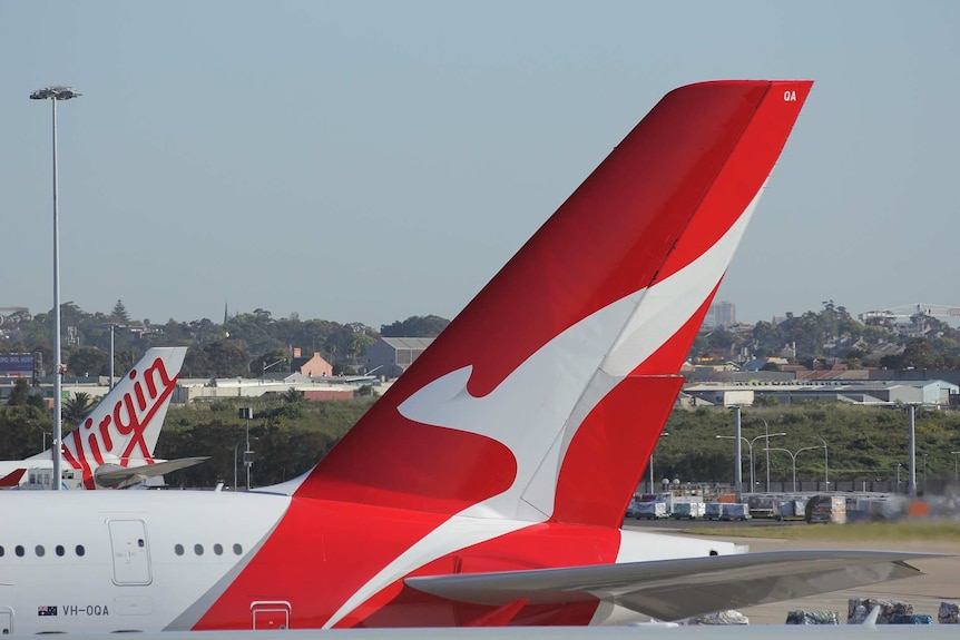 A Virgin Australia plane and a Qantas plane sit on a runway.