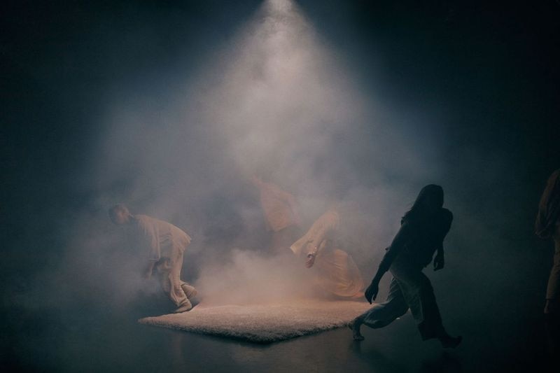 Dancers move on stage against a smokey backdrop.