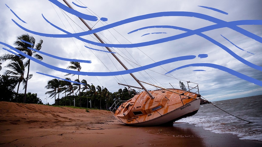 A sailing boat washed up on a beach beach in windy conditions.