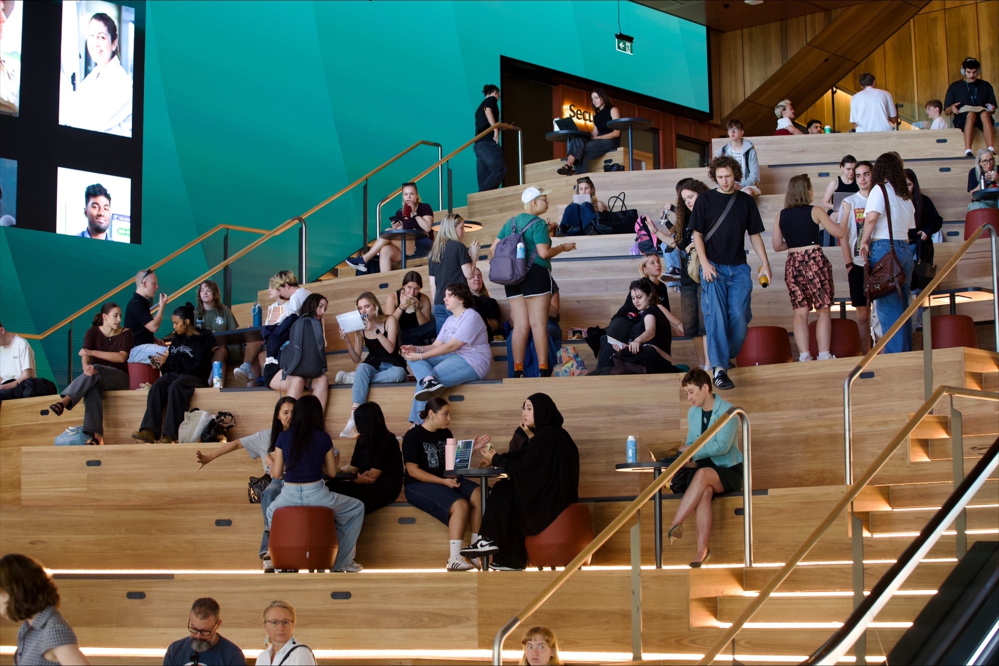 Um edifício de vários andares cor de mostarda com terraços e gramados ao redor. 