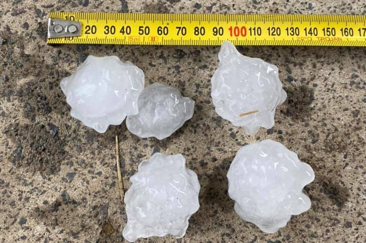 Hailstones are seen next to a measuring tape, showing them to be about four or five centres across.