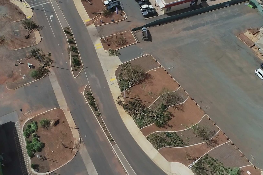 Drone footage shows trees felled in a red-earthed town.