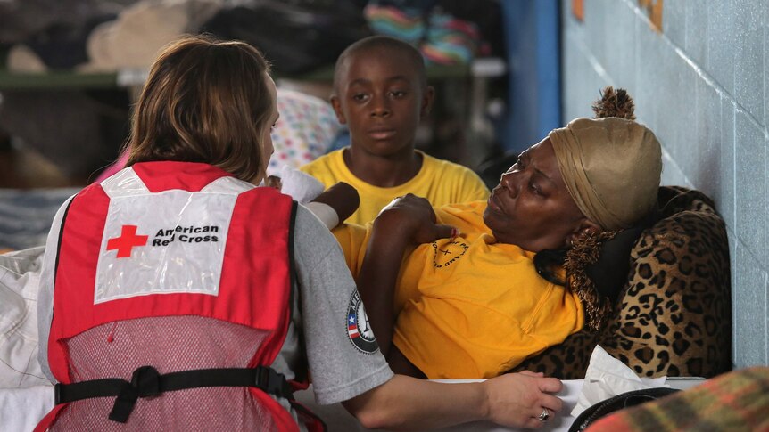 A Red Cross worker speaks with a flood evacuee at a shelter set up in a high school gym at Kentwood, Louisiana.
