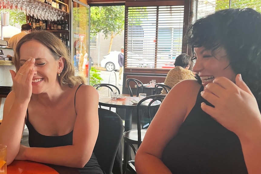 Two people laughing in a restaurant.