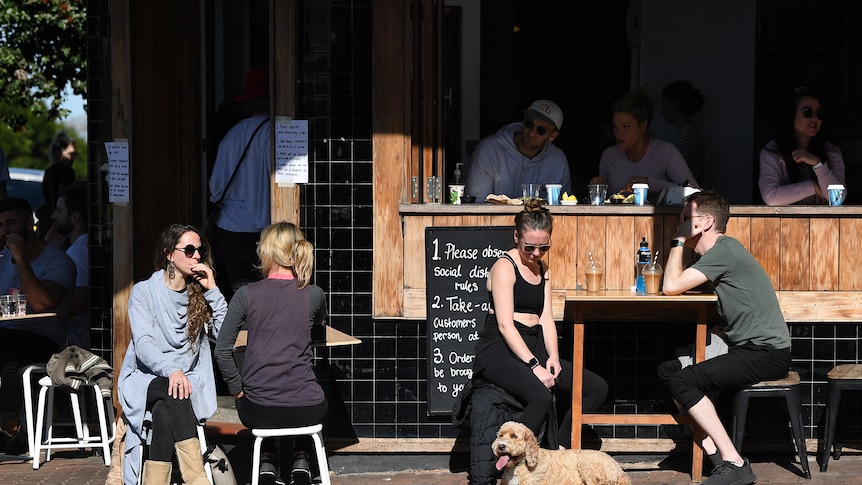 people sitting at tables in front of a cafe