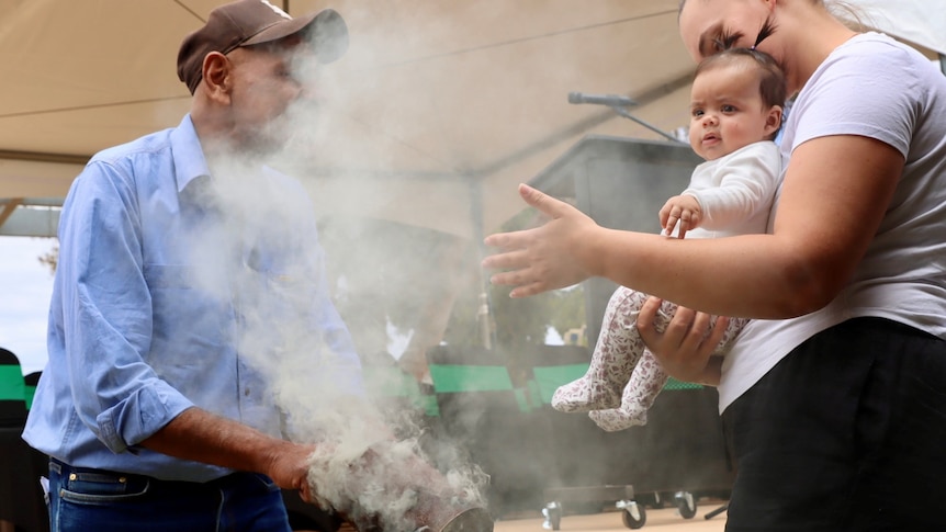 An elder cleanses a baby with the smoke