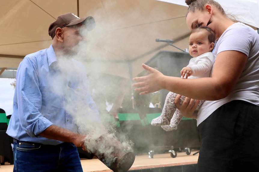 An elder cleanses a baby with the smoke