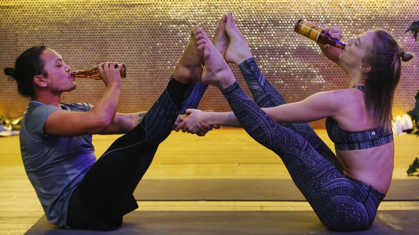 Two participants in Melbourne beer yoga class doing poses while drinking beer.