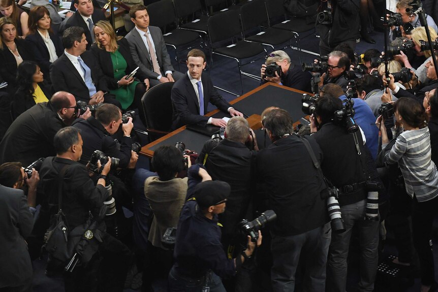 Facebook CEO, Mark Zuckerberg surrounded by reporters and photographers.