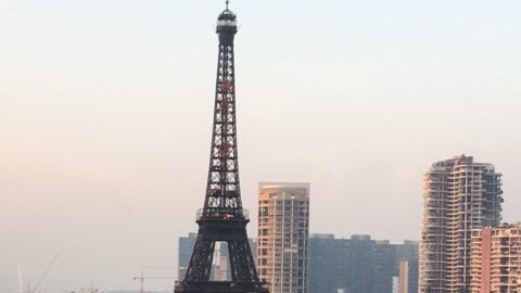 A replica Eiffel Tower stands next to apartment towers.