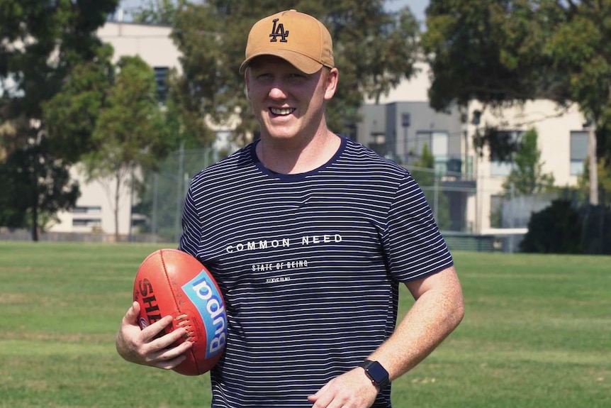 Josh Green holds a football at a park in Melbourne.