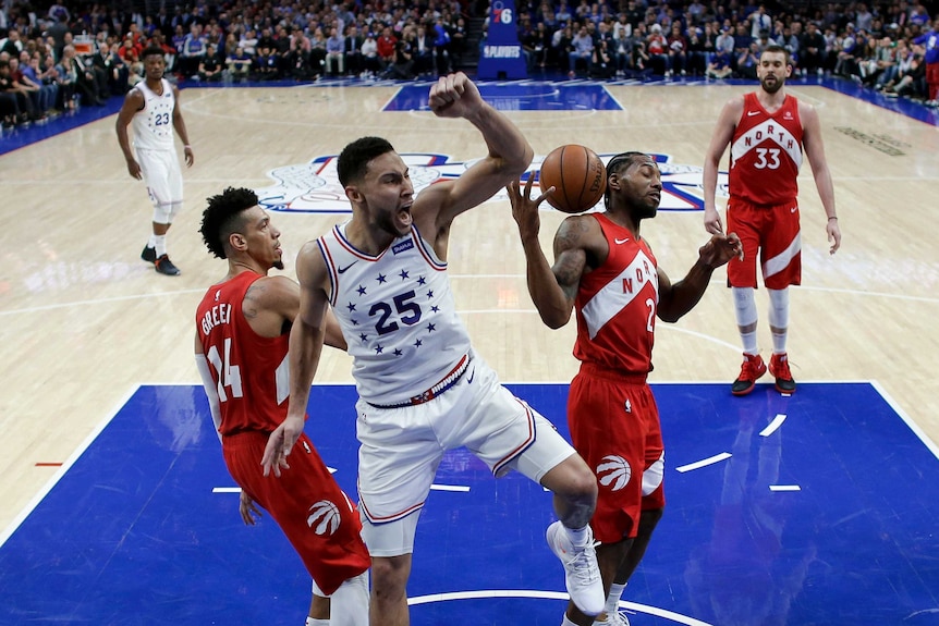 Ben Simmons clenches his fist above his head and yells as the ball bounces behind him