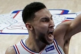 Ben Simmons clenches his fist above his head and yells as the ball bounces behind him