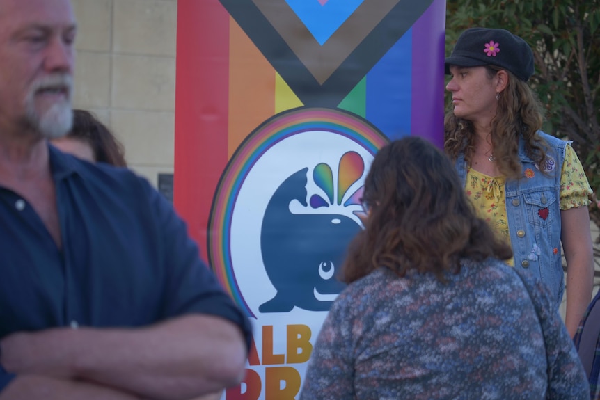 A group of people standing in front of an Albany Pride sign.