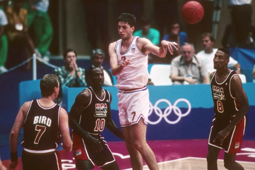 Croatia's Toni Kukoc jumps in the air to throw a pass. Larry Bird, Clyde Drexler and Scottie Pippen of Team USA surround him.