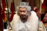 Queen Elizabeth arrives at Westminster wearing a gown and a crown.