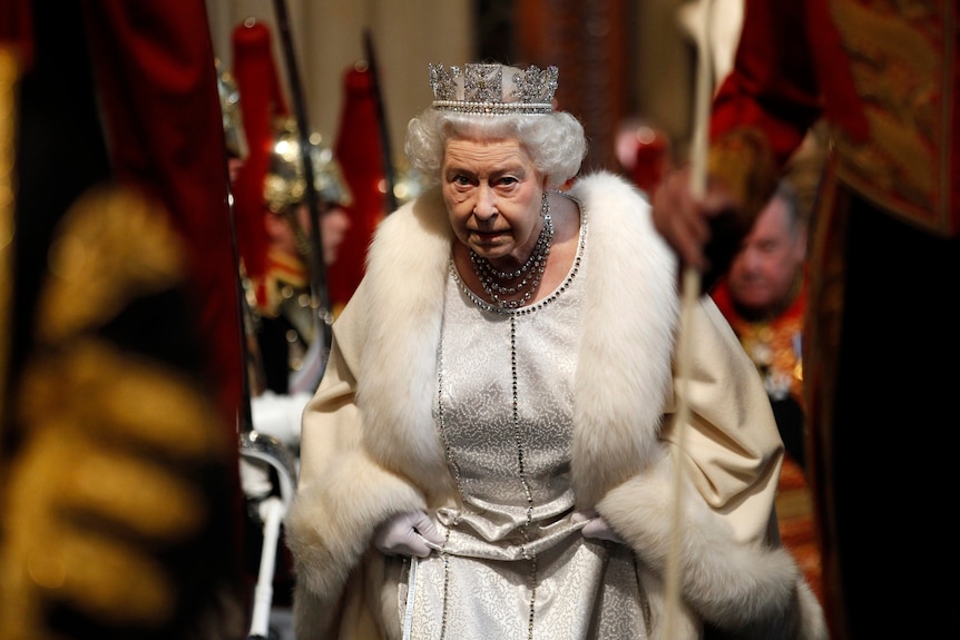 Regina Elisabeta sosește la Westminster purtând un halat și o coroană.