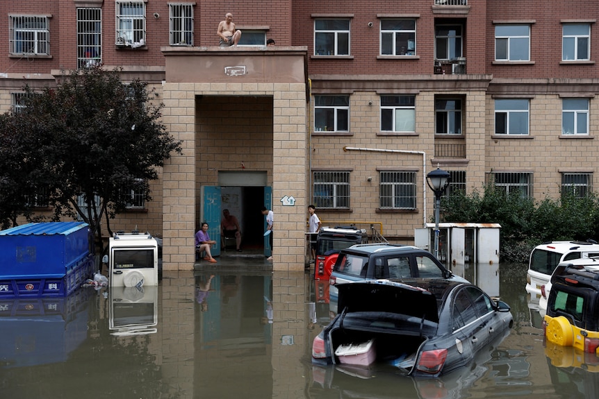 People stay on a roof at a flooded residential compound after typhoon in China.