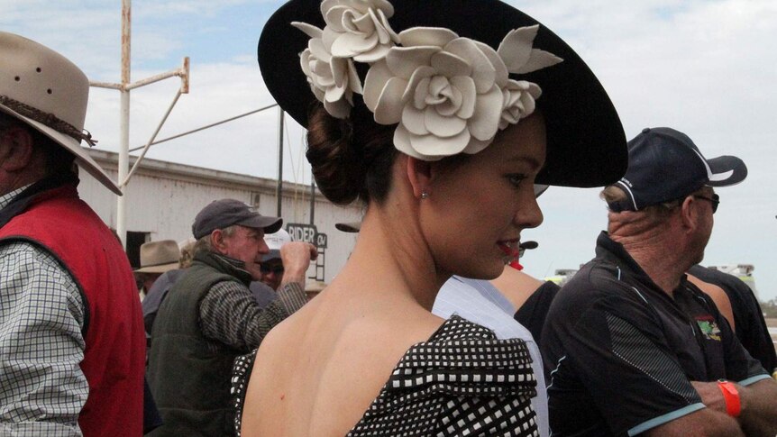 A young woman in a black and white dress and elaborate hat waits for the judging of the Fashions in the Field at the Louth Races