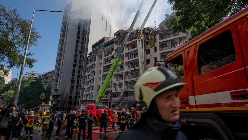 Firefighters outside a building that was hit by air strikes.