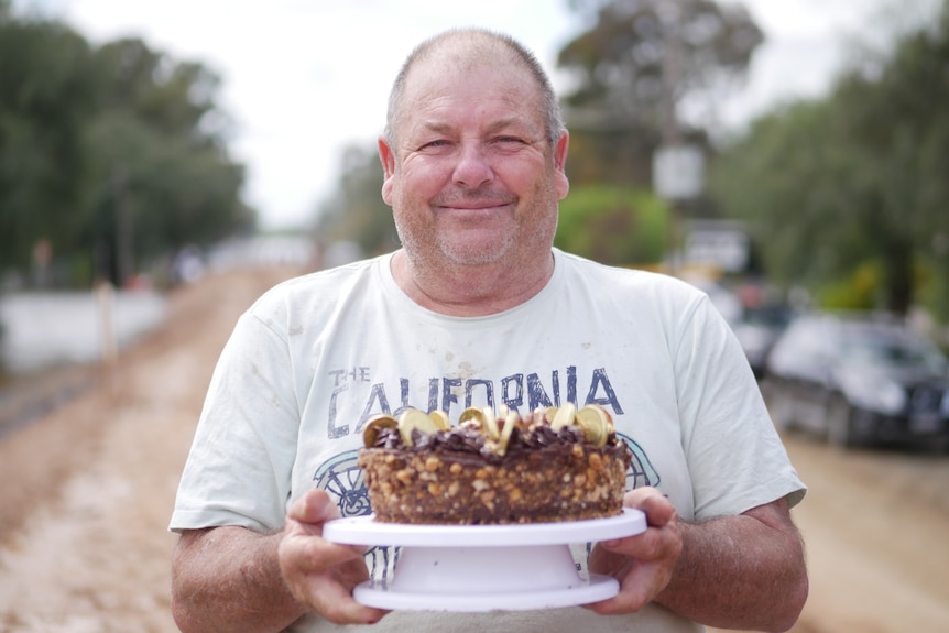 A man holding a birthday cake in the street