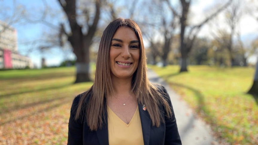 A woman stands smiling at the camera.