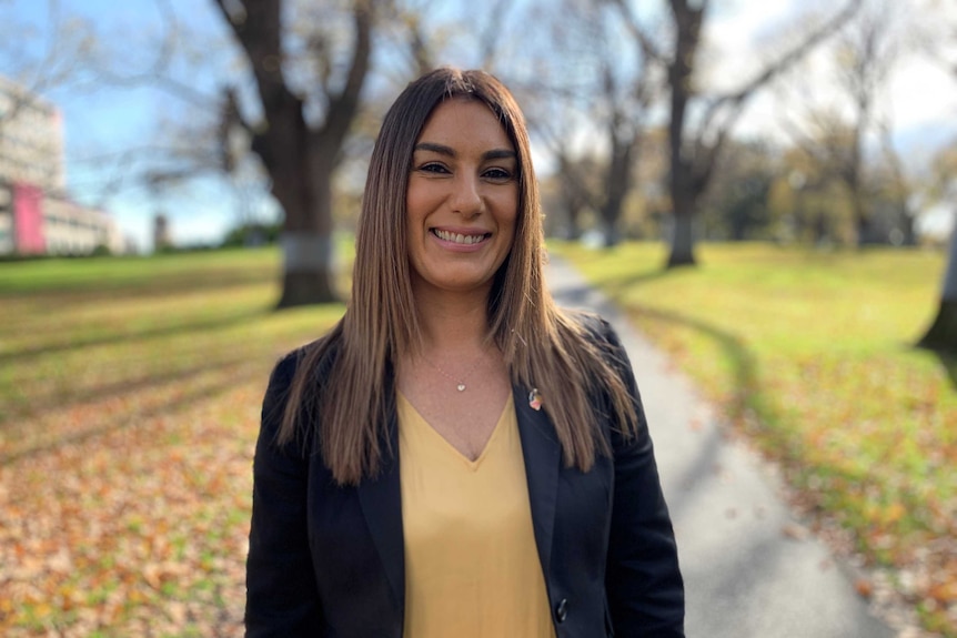 A woman stands smiling at the camera.