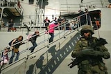 A Greek soldier stands guard as people board a Greek frigate in an attempt to flee Lebanon