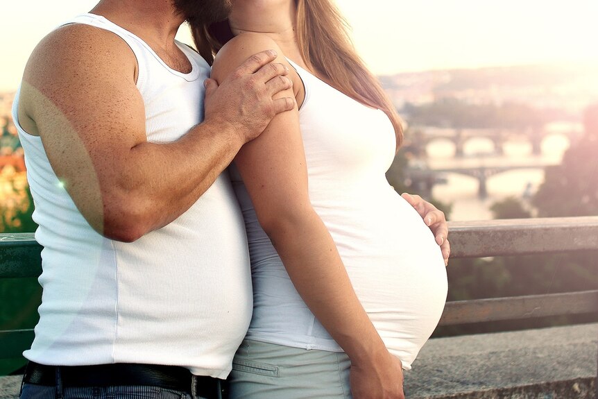 A man puts his arm around a pregnant woman