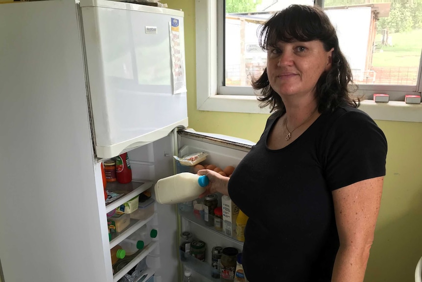 A woman putting milk in the fridge.