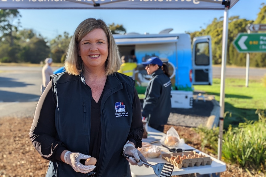 Woman in blue vest in front of a table of food