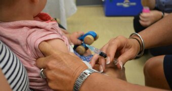 A nurse prepares to give a needle to a baby.