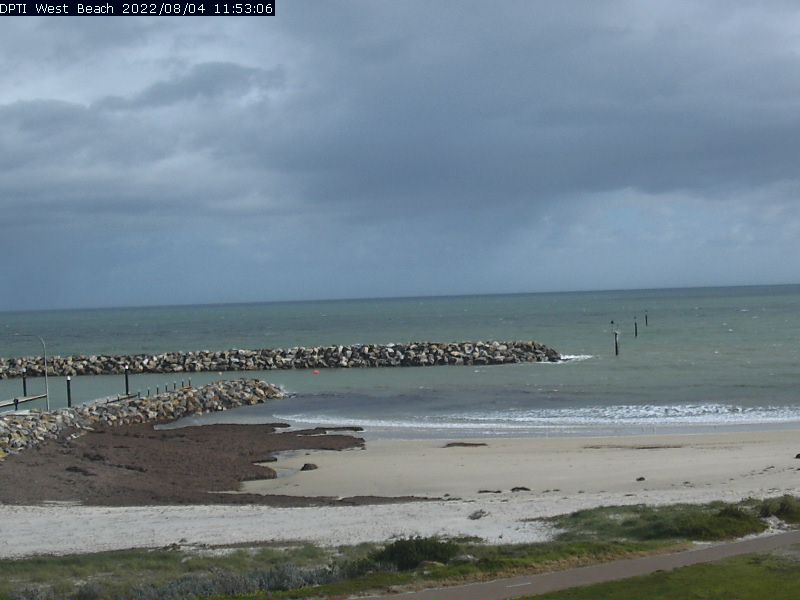 Rock groynes and a beach with seaweed on it with storm clouds