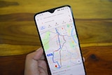 A hand holds a phone looking at a route on the Google Maps app