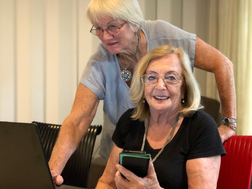Two older women sitting in front of laptops