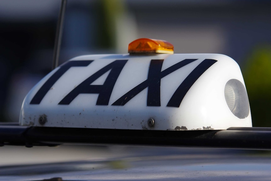 A tight shot of a taxi sign and light on the roof of a Swan Taxis car.