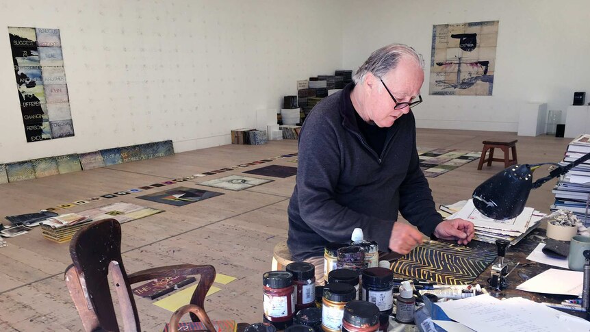 A man working on a painting in a big studio