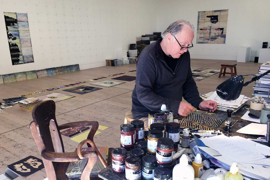 A man working on a painting in a big studio