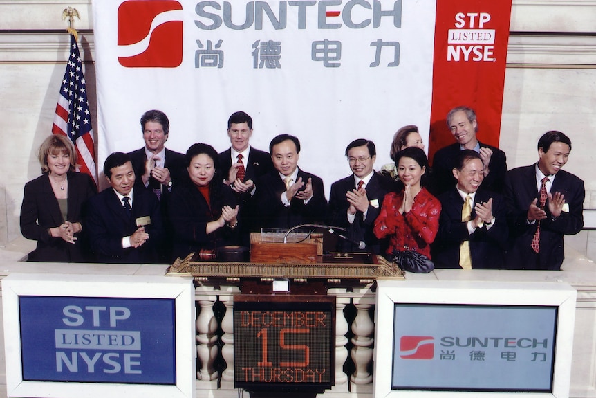 十二个人在 SunTech 和 NYSE 横幅两侧的舞台上鼓掌