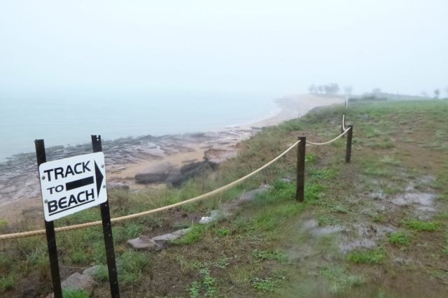 A photo of a sign pointing towards a beach.