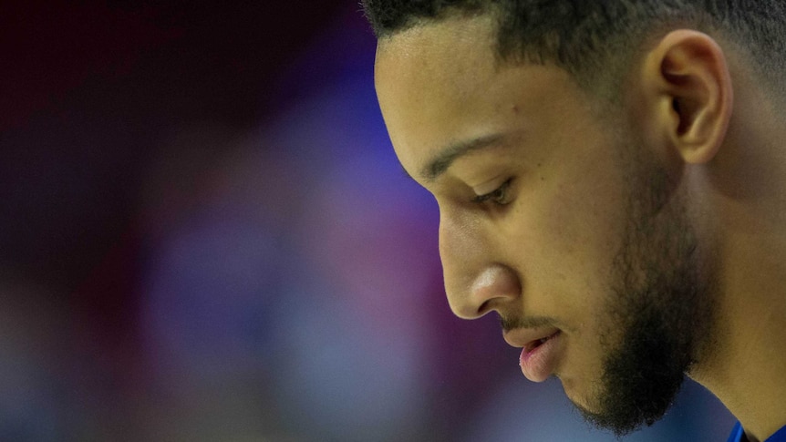 NBA player Ben Simmons is seen in profile, looking down.