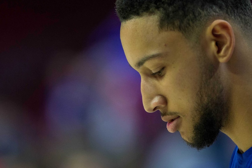 NBA player Ben Simmons is seen in profile, looking down.