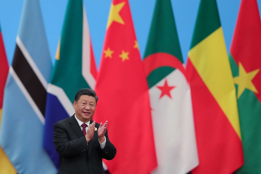 China's President Xi Jinping claps and smiles.
