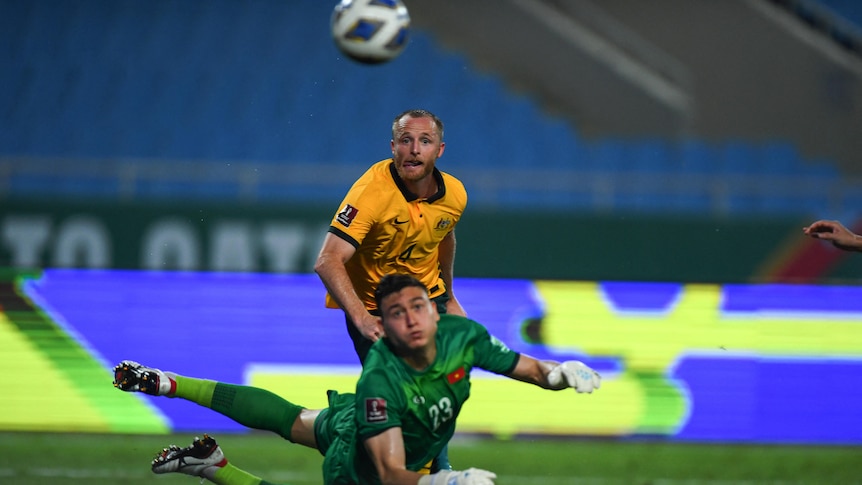 Rhyan Grant watches as the ball sails past the Vietnamese goalkeeper, who is diving backwards and looking at the ball