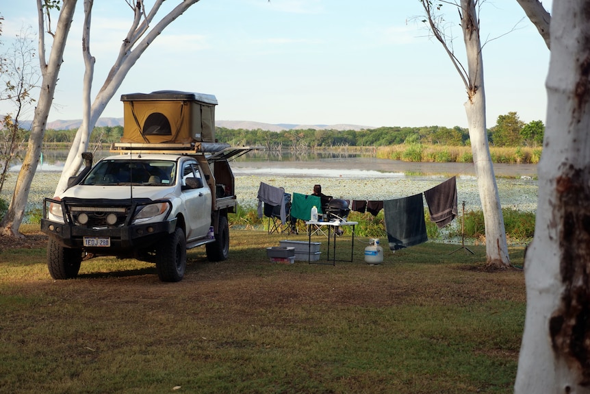 A ute is parked next to a lakeside camp site.