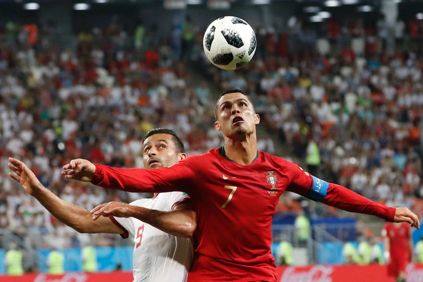 Portugal's Cristiano Ronaldo (R), and Iran's Omid Ebrahimi challenge for the ball at the World Cup.