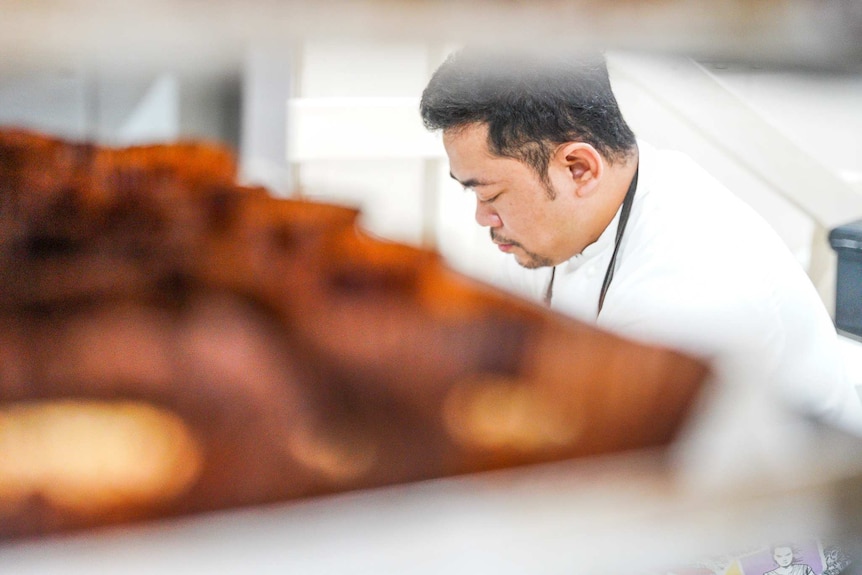 Un homme portant des vêtements de chef regarde un banc.