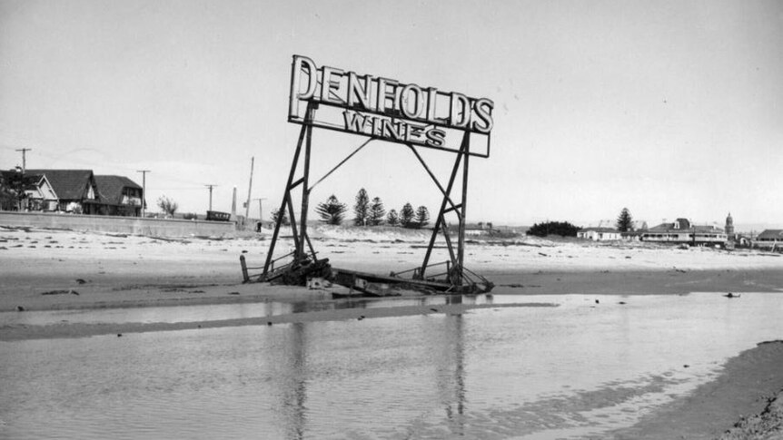 black and white image of large frame of a neon sign washed up on a beach