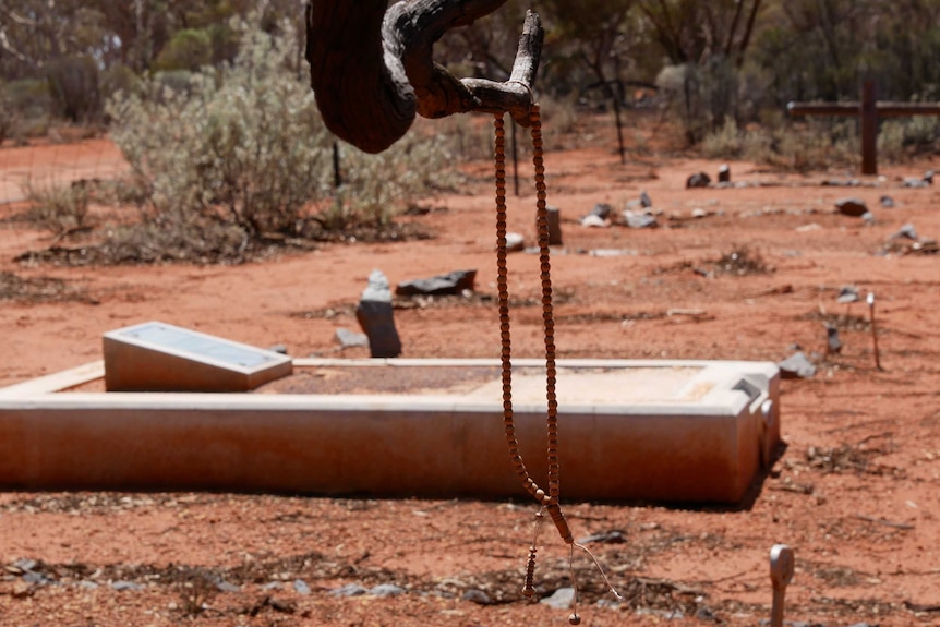 A religious necklace hanging on a branch in an outback cemetery