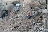 A civilian collects tree branches amid the rubble of a damaged site in the rebel-held besieged Qadi Askar neighbourhood of Aleppo, Syria